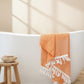 A green body towel with a herringbone pattern is draped over the edge of a bathtub, displaying its texture and color.