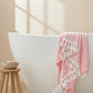 A green body towel with a herringbone pattern is draped over the edge of a bathtub, displaying its texture and color.